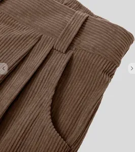Detail van een bruine corduroy broek met hoge taille, riemlussen en steekzakken