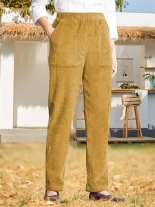 Detail of ginger yellow corduroy trousers featuring elastic waist and large patch pockets