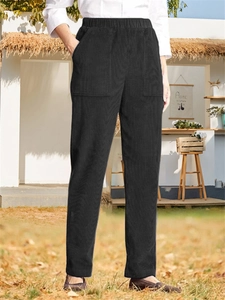 Detail of high-waist elastic band and side patch pockets on black corduroy trousers