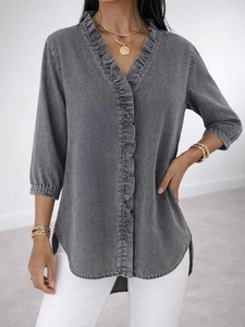 Detail view of ruffle trim V-neck and denim-style fabric on women casual blouse