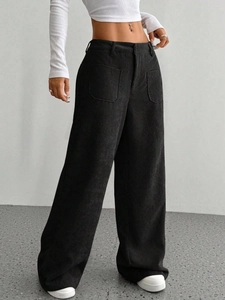 Dettaglio dei pantaloni neri in velluto a coste a vita alta con tasche applicate frontali