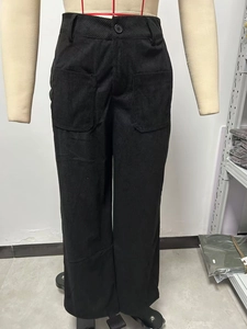Dettaglio di pantaloni neri in velluto a coste a vita alta con tasche a toppa e bottone
