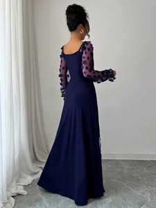 Macro shot of the rear view showing 3D floral appliques on the mesh sleeves of a blue gown
