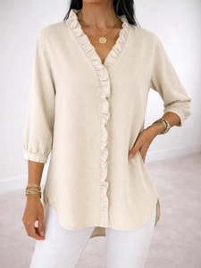 Detail of V-neck ruffle trim and irregular curved hem on beige casual ladies shirt