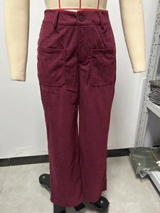 Dettaglio dei pantaloni a gamba larga in velluto bordeaux con vita alta e tasche quadrate