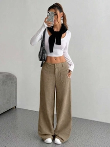 Dettaglio dei pantaloni larghi in velluto a coste kaki con ampie tasche anteriori e stile