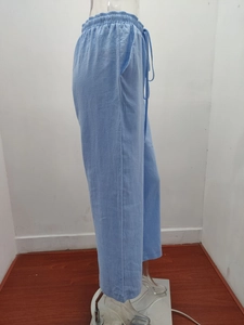 Detail view of light blue cotton linen pants featuring elastic drawstring waist and side pockets