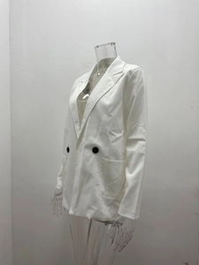 Detail of white double-breasted blazer showing black buttons and large patch pockets