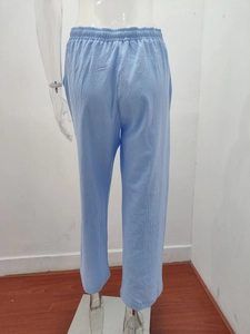 Detail view of high-waist elastic waistband and cotton linen texture on light blue pants