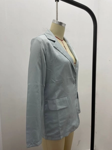 Detail of light blue satin blazer showing smooth texture and single button closure