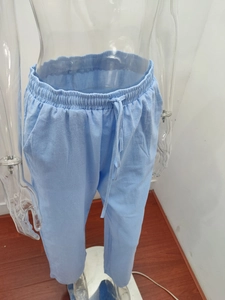 Detail of light blue linen pants featuring elastic drawstring waist and side pockets