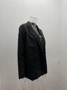 Side view detail of black double-breasted blazer showing notch lapel and flap pockets