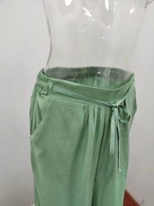 Dettaglio dei pantaloni larghi verde salvia con coulisse in vita e tasche laterali