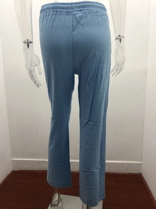 Detail of light blue linen trousers with an elastic waistband and natural fabric texture