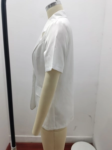 Detail view of white short-sleeved blazer collar and symmetrical flap pocket design