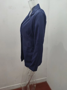 Detail of navy blue blazer featuring classic lapels and flap pockets on smooth fabric