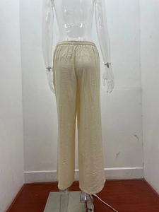 Dettaglio dei pantaloni a gamba larga a vita alta con coulisse elastica e trama lino