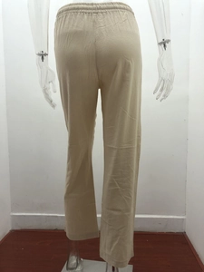 Detail of the elastic waistband and textured linen fabric on beige wide-leg trousers