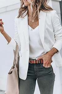 Close-up of white blazer jacket with notched lapel and layered gold necklace styling