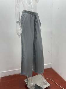 Dettaglio dei pantaloni grigi a gamba larga con vita alta elastica e coulisse regolabile