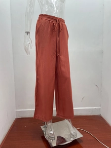 Dettaglio di pantaloni a gamba larga a vita alta rosso mattone con coulisse elastica regolabile