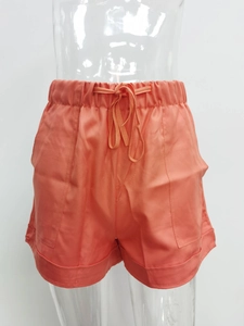 Detail of coral orange high waisted casual shorts featuring drawstring waist and wide hem