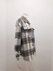 Detail view of plaid flannel shacket with flap pockets and brown checkered wool pattern