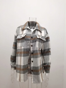 Detail of plaid shacket featuring front button closure and dual flap chest pockets
