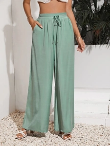 Dettaglio dei pantaloni a gamba larga a vita alta in verde chiaro con coulisse