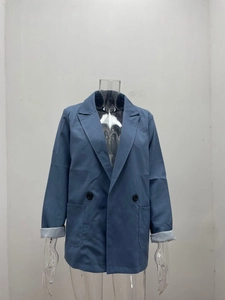 Detailed view of dusty blue blazer featuring peak lapels and stylish cuffed grey sleeves