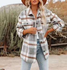 Brown plaid wool shacket with chest pockets and round buttons in a fall outdoor setting