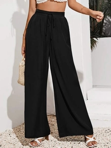 Scatto all'aperto di pantaloni neri a gamba larga a vita alta con elegante fiocco in vita