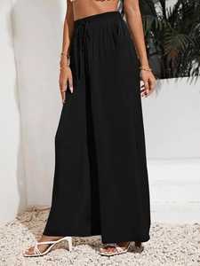 Dettaglio dei pantaloni neri a gamba larga a vita alta con coulisse elastica e tasche laterali