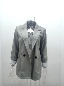 Detail view of a gray casual blazer featuring folded cuffs with white lining and large pockets
