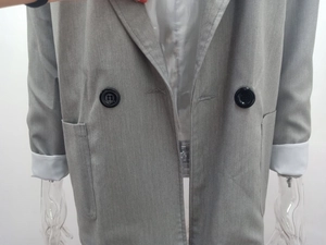 Detailed view of gray double-breasted blazer with button closure and large front pockets