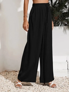Dettaglio dei pantaloni neri a gamba larga con vita alta elastica, coulisse e tasche laterali