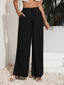 Dettaglio dei pantaloni neri a vita alta con coulisse e gamba larga per l'estate
