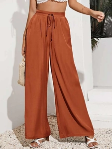 Dettaglio dei pantaloni larghi a vita alta arancione ruggine con coulisse e seta fluida