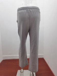 Detail view of the elastic waistband and straight leg cut of grey linen trousers