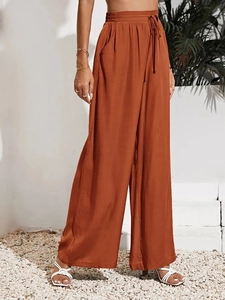 Dettaglio dei pantaloni a vita alta rosso ruggine con coulisse e tasche laterali capienti