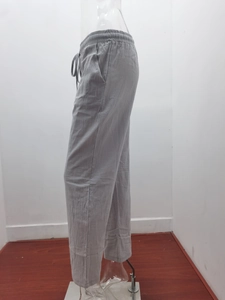 Detail of light grey cotton linen trousers with elastic drawstring waist and side pockets