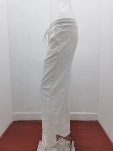 Detail of white cotton linen trousers with elastic drawstring waist and side pockets