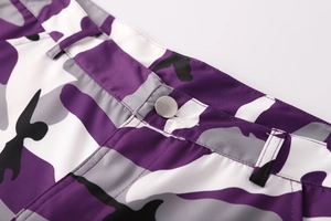 Dettaglio dei pantaloni cargo mimetici viola con tessuto twill e bottone in metallo