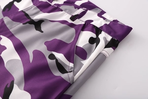 Dettaglio dei pantaloni cargo mimetici viola con tasche laterali e passanti