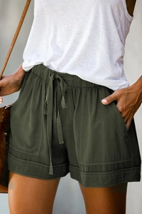 Detail of high-waist olive green linen shorts featuring a drawstring and utility pockets