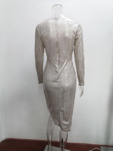 Detail of silver sequined bodycon dress with long sleeves and asymmetrical slit hemline
