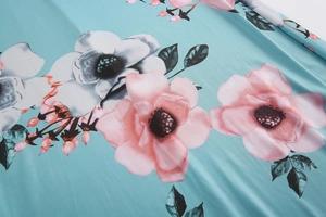 Detailaufnahme von Blumenprint-Stoff mit rosa Blüten auf türkisem Hintergrund