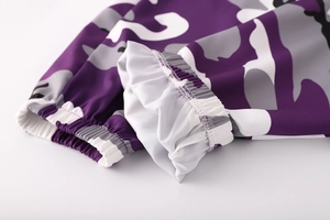 Dettaglio dei pantaloni cargo mimetici viola con polsini elastici a costine e cuciture