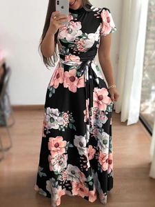Detail eines schwarzen Maxikleids mit rosa Blumendruck und Bindegürtel an der Taille