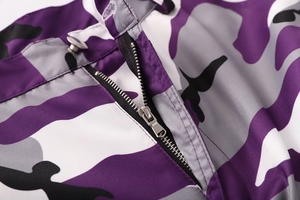 Dettaglio macro di pantaloni mimetici viola con cerniera metallica e chiusura a bottone